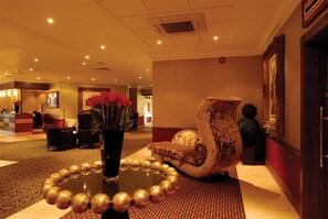 A lobby with a reception desk, a seating area with a round table, and a decorative vase. - Preston Leyland BW Signature Collection (Leyland)