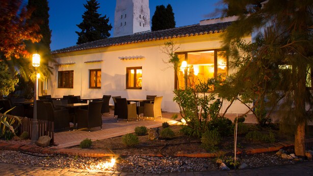 A building with a tower, outdoor seating, and a garden. - Hotel & Spa La Salve (Torrijos)