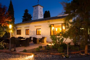 A building with a tower, outdoor seating, and a garden.