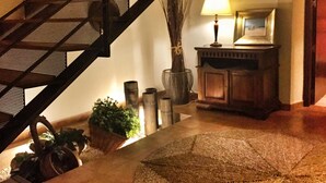 A staircase with a metal railing, a lamp, a vase with branches, and a cabinet with a picture on top. - Hotel & Spa La Salve (Torrijos)