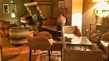 Un salon chaleureux avec des meubles en osier, une table basse en verre et une cheminée.