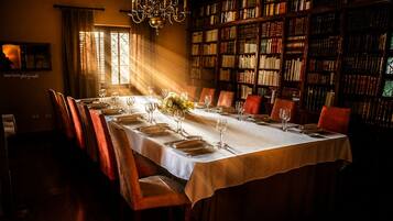 Comedor con una larga mesa dispuesta para una comida, rodeado de estanterías llenas de libros.