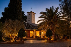A building with a tower, surrounded by palm trees and potted plants. - Hotel & Spa La Salve (Torrijos)