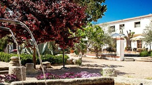 A courtyard with a fountain, stone structures, and a building with windows and doors. - Hotel & Spa La Salve (Torrijos)