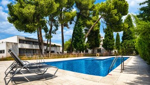 A swimming pool with lounge chairs, surrounded by trees and a building with a modern design. - Hotel & Spa La Salve (Torrijos)