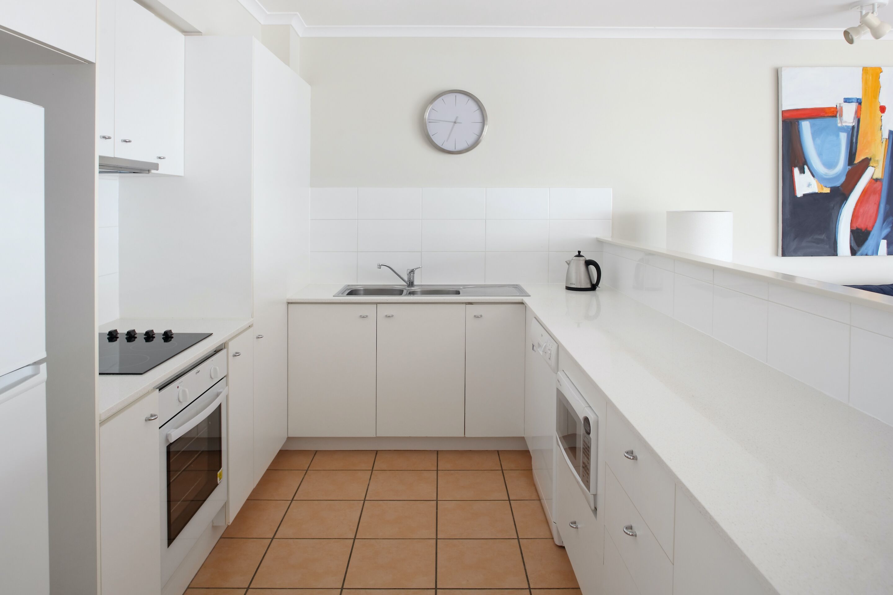 A modern kitchen with white cabinets, a stove, oven, and a sink.