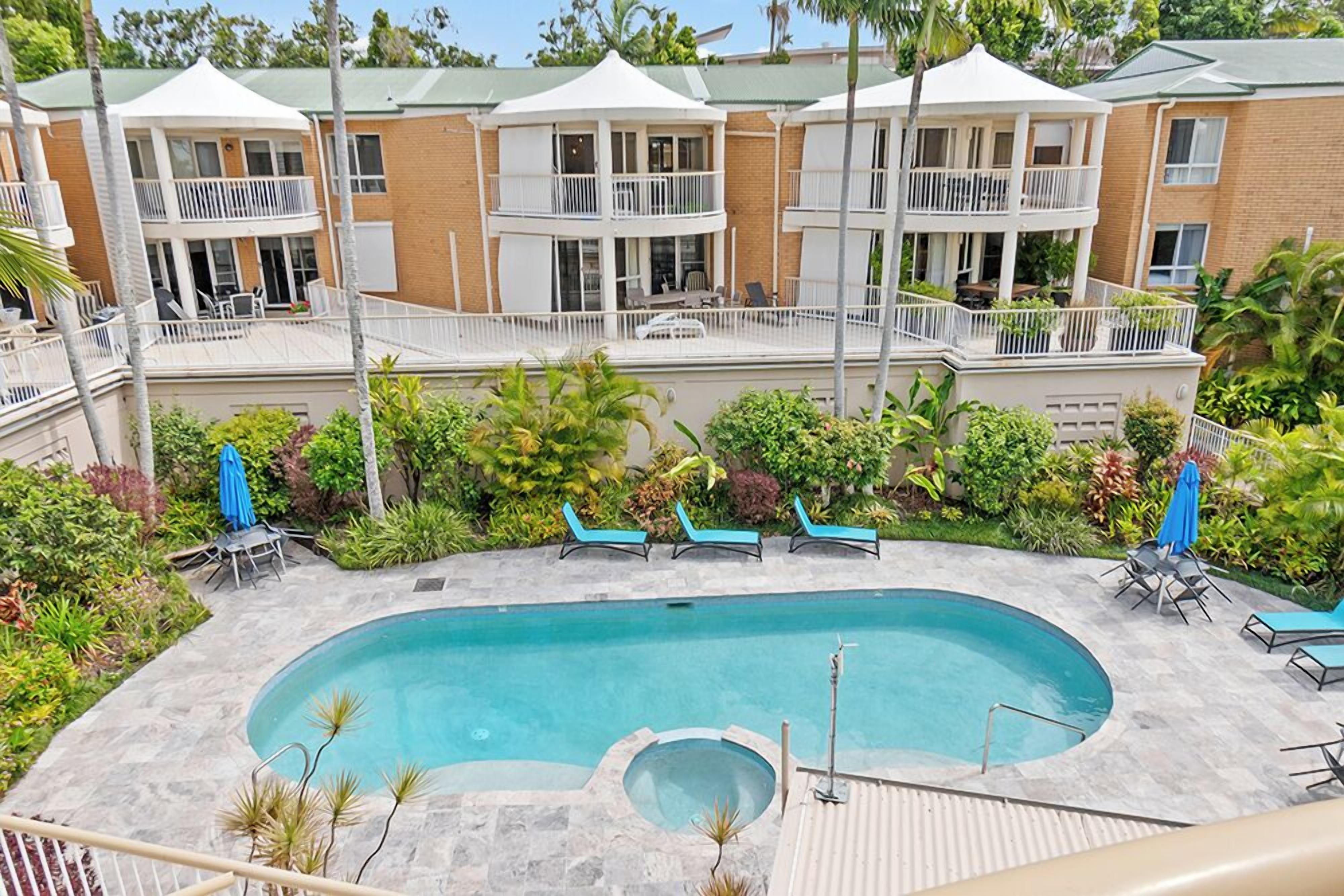 Un hotel con piscina, varios balcones y mobiliario de exterior.