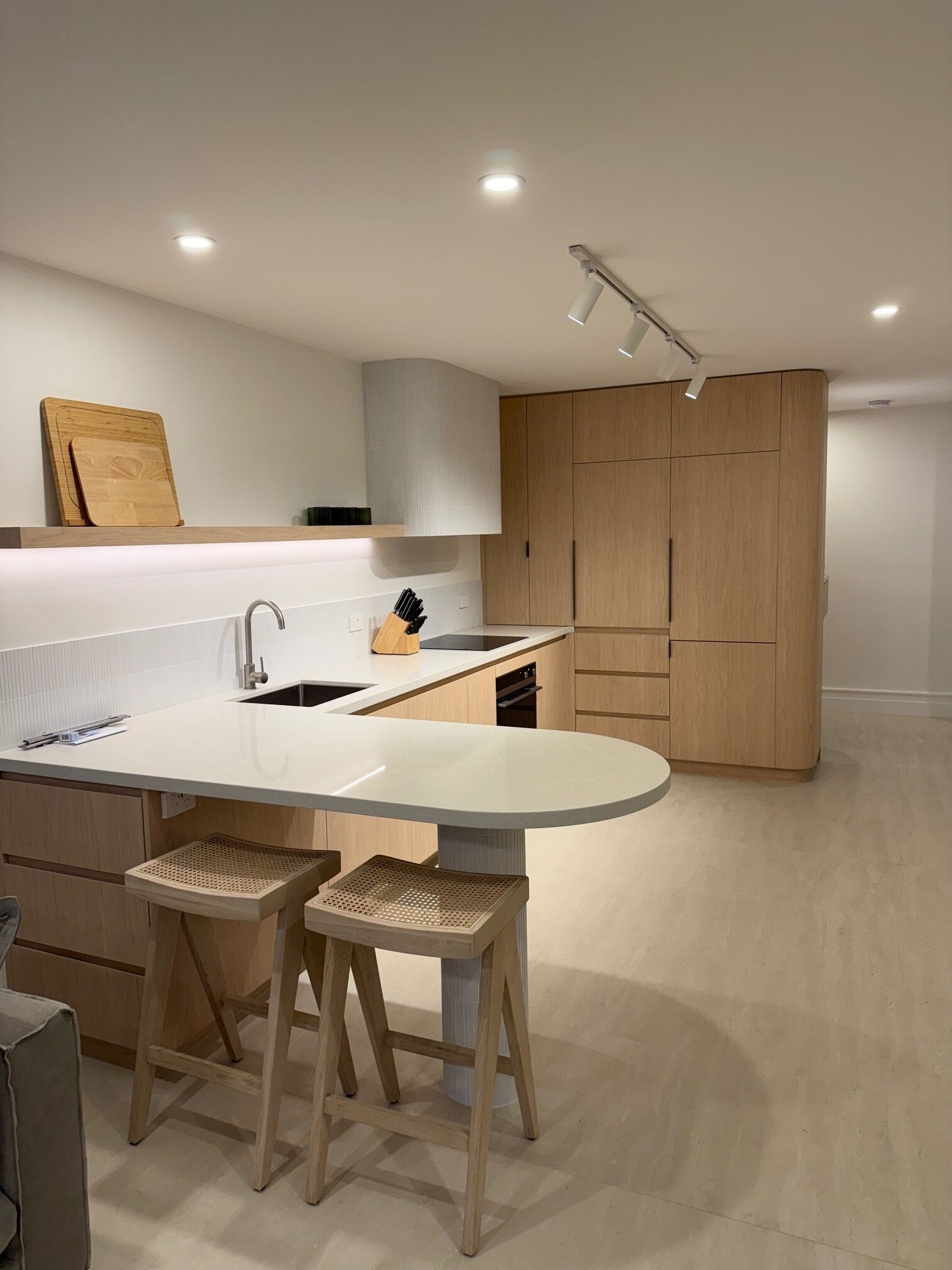 Eine moderne Küche mit einer zentralen Kochinsel, Holzschränken und einem eingebauten Backofen.