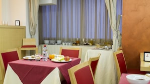 A dining area with tables set for breakfast, including plates of food, drinks, and a fruit bowl. - Hotel Catania Town (Catania)