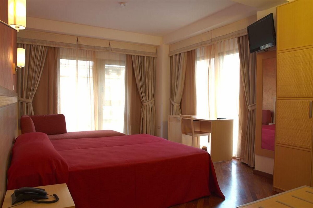 Una habitación de hotel con una cama grande, un escritorio y un televisor.