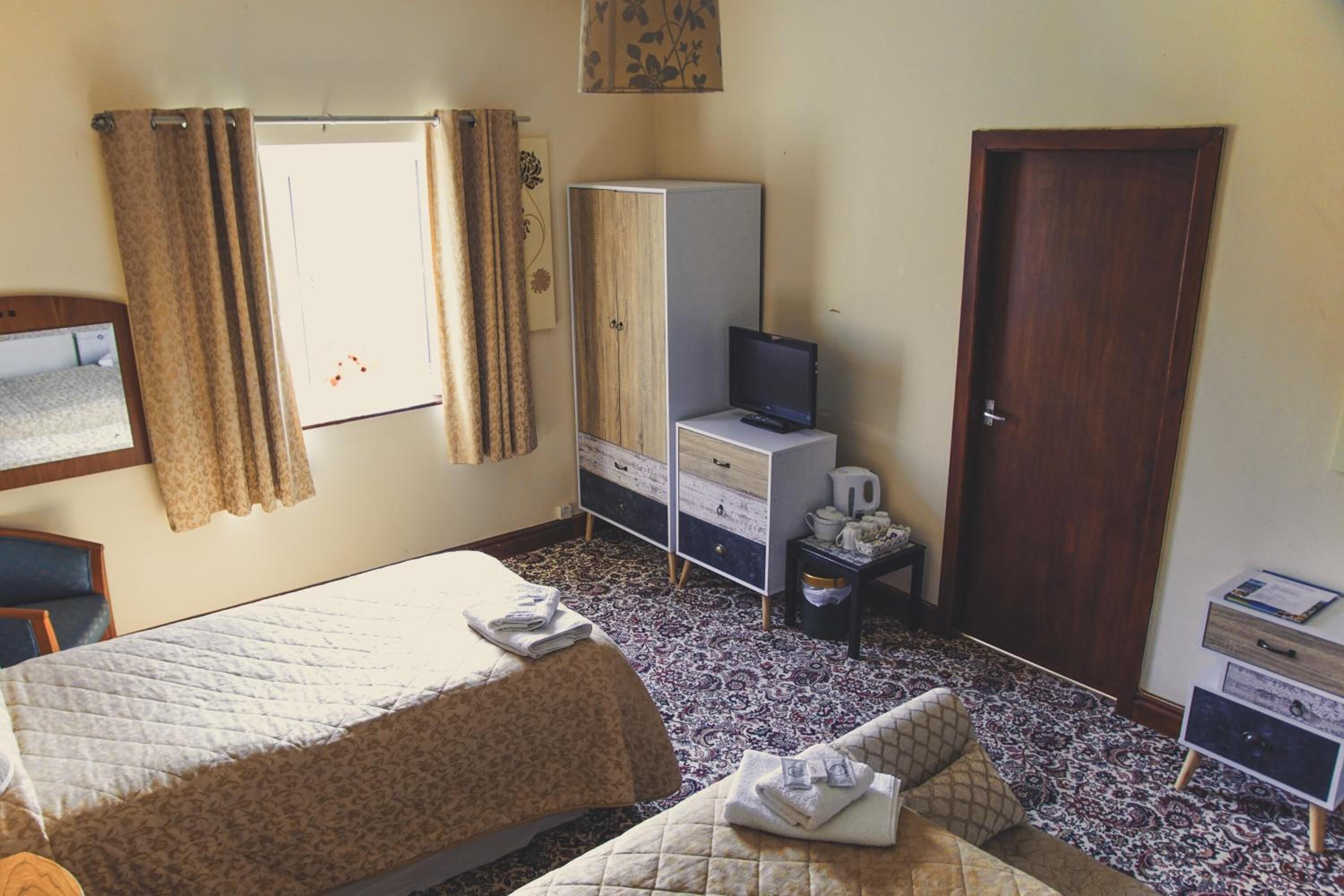 A bedroom with a bed, a wardrobe, a television, and a door.