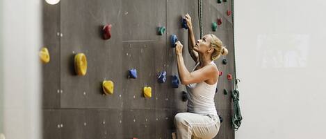 A person climbing a wall with various colored holds.