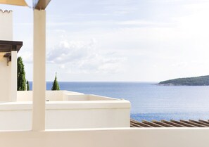 Una terraza con vista al mar y una colina distante.