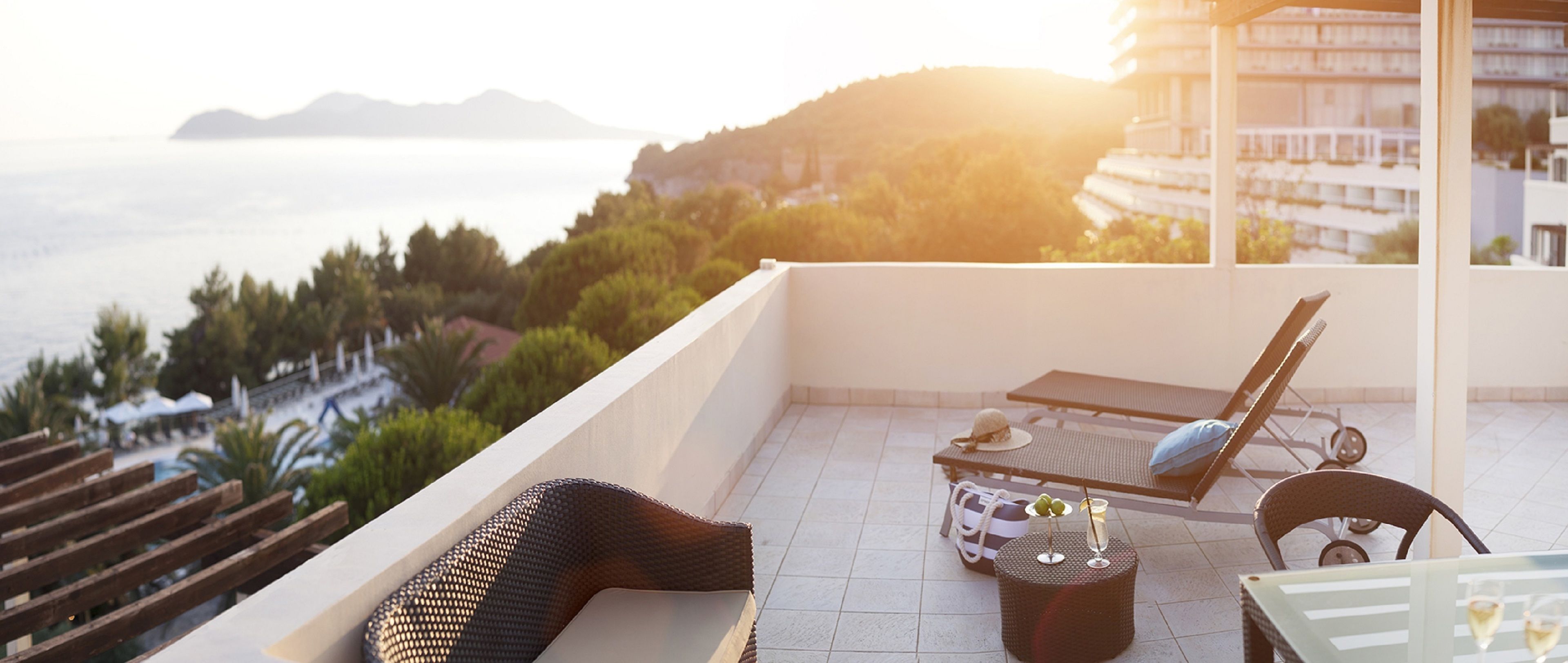 Un balcon avec un canapé en osier, une table avec des boissons et un fauteuil de relaxation.