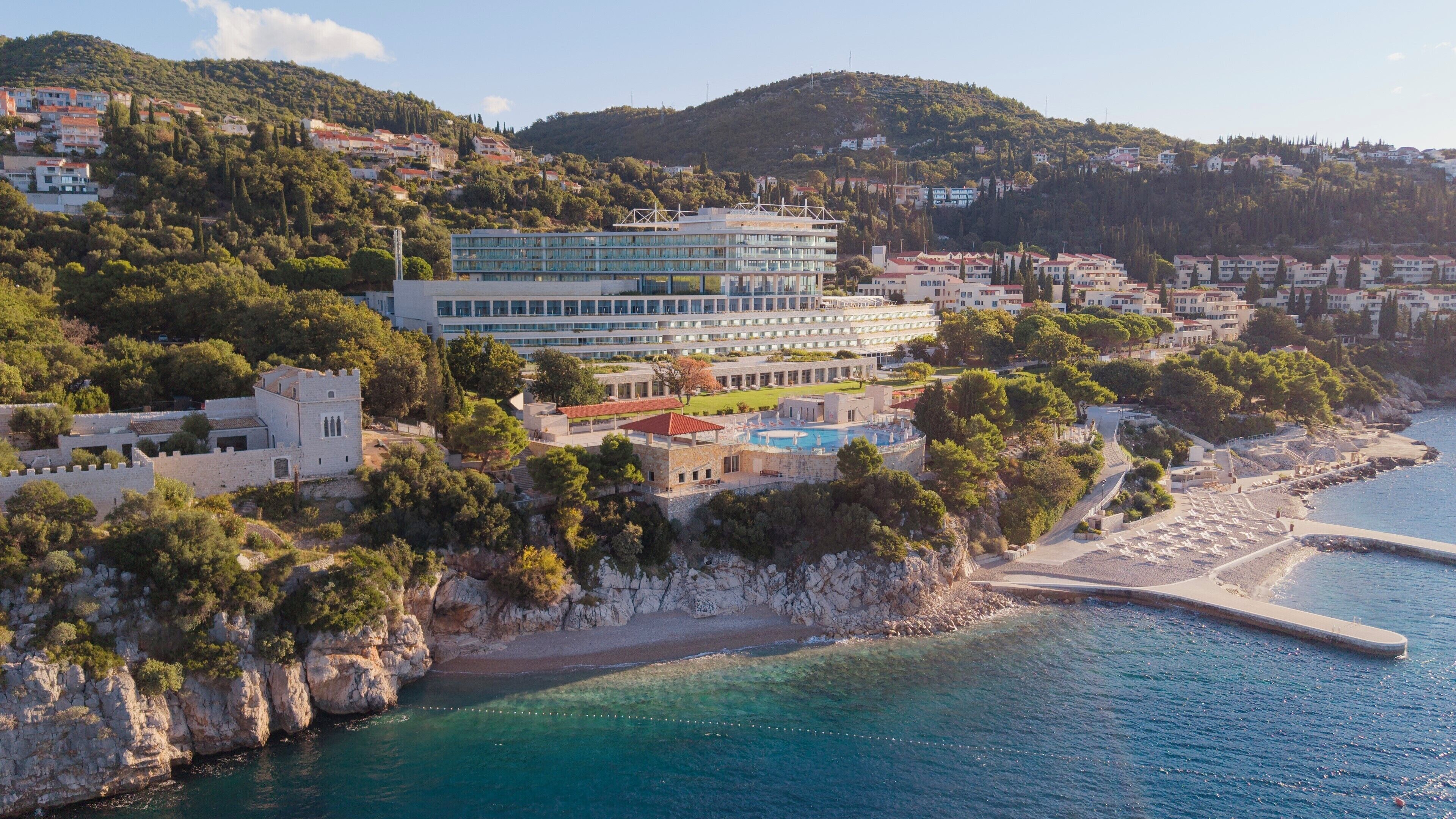Un hotel frente al mar con piscina, una estructura tipo castillo y vistas al océano.