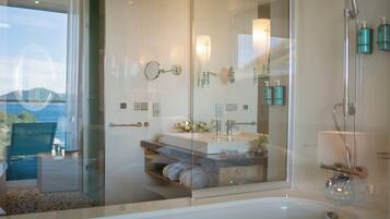 A modern bathroom with a glass shower enclosure, a bathtub, and a vanity with a mirror and towel rack.