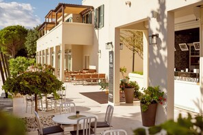 Un patio con mobiliario exterior, una pérgola y macetas con plantas.
