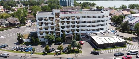 Un hotel de varios pisos con un patio central, rodeado por un estacionamiento y vistas al agua.