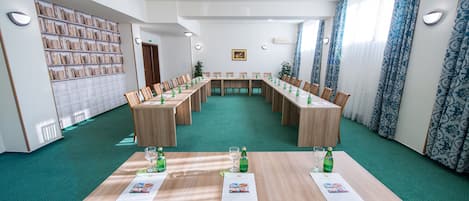 A conference room with a long table, multiple chairs, and bookshelves.