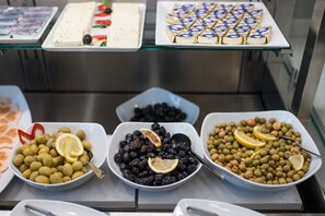 A buffet with various dishes including olives, blackberries, and a dessert tray. - Hotel Oxford (Constanta)