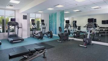 Un gimnasio con cintas de correr, elípticas y bancos de pesas.