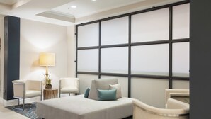 A modern hotel room with a large bed, two armchairs, a small side table with a lamp, and a large window with blinds. - Residence Inn by Marriott Fort Myers Sanibel (Fort Myers)