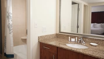 Un baño con lavamanos, espejo y cortina de ducha.