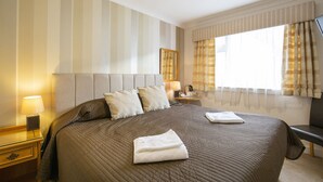 A neatly made bed with pillows, a bedside lamp, and a folded towel on the bed. - Arden Guest House, Craigmillar Castle Edinburgh (Edinburgh)
