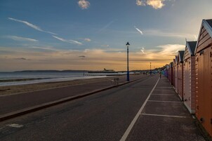 A seaside promenade with wooden buildings, a bench, and a street lamp.