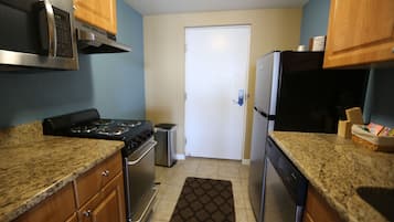 A compact kitchen with granite countertops, stainless steel appliances, and wooden cabinets.