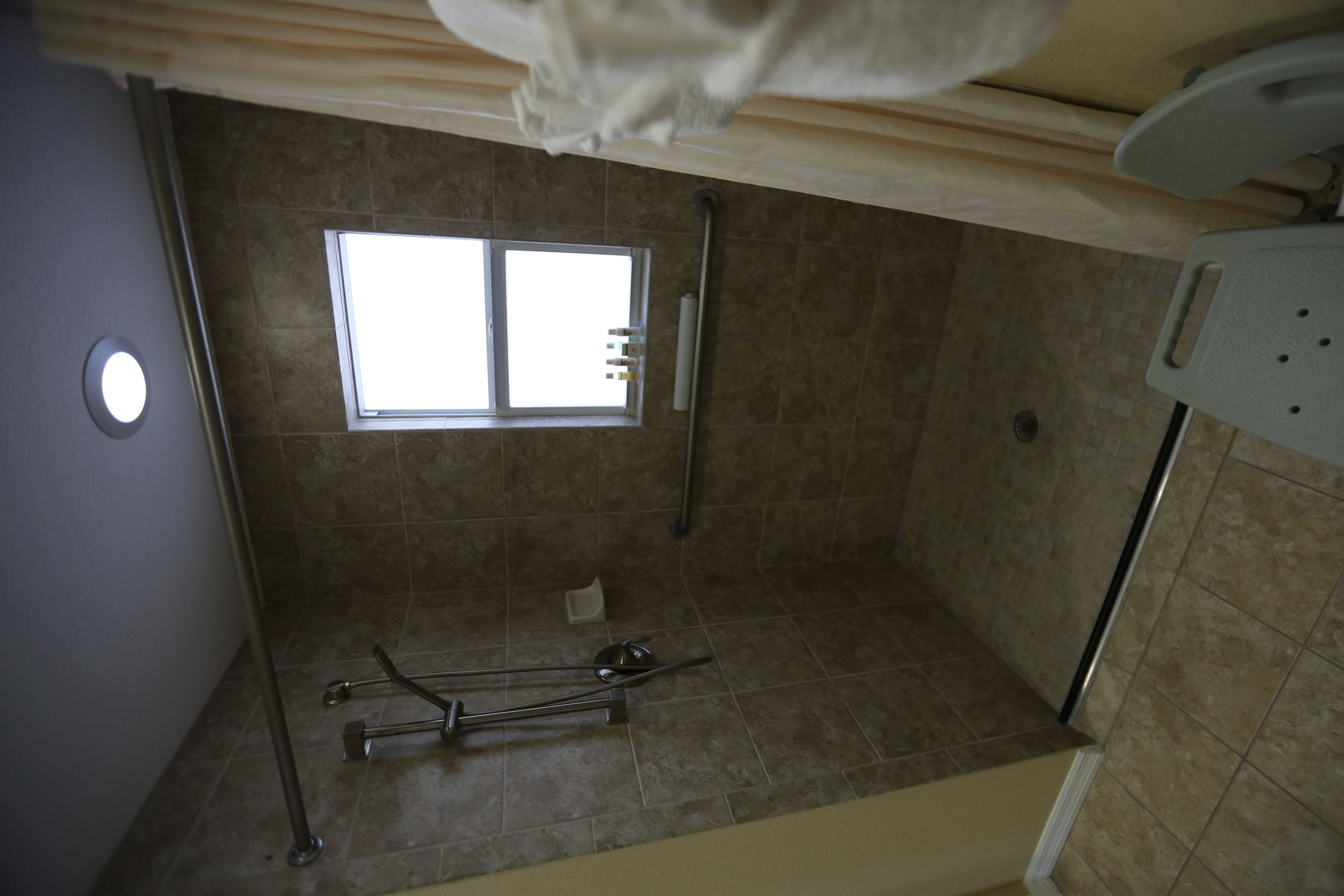 Een badkamer met raam, douche en toilet.