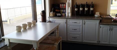 A kitchen with a white countertop, a dining table with four chairs, and a window with a view of a building.