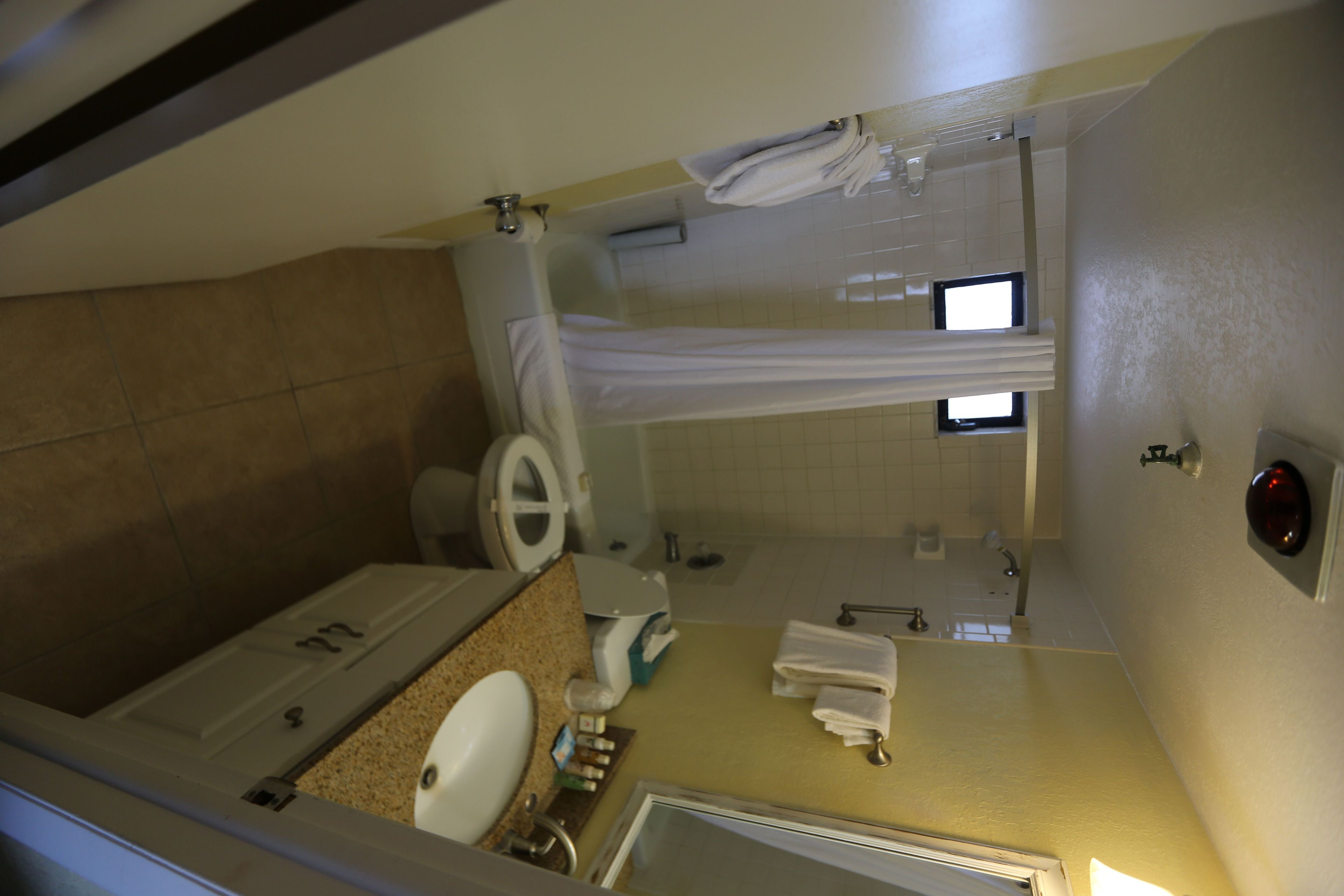 A compact bathroom with a toilet, sink, and shower area.