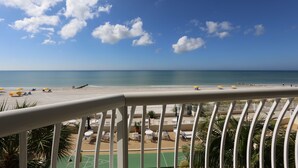 Une vue sur la plage depuis un balcon doté d’une balustrade, une plage de sable et une mer calme.