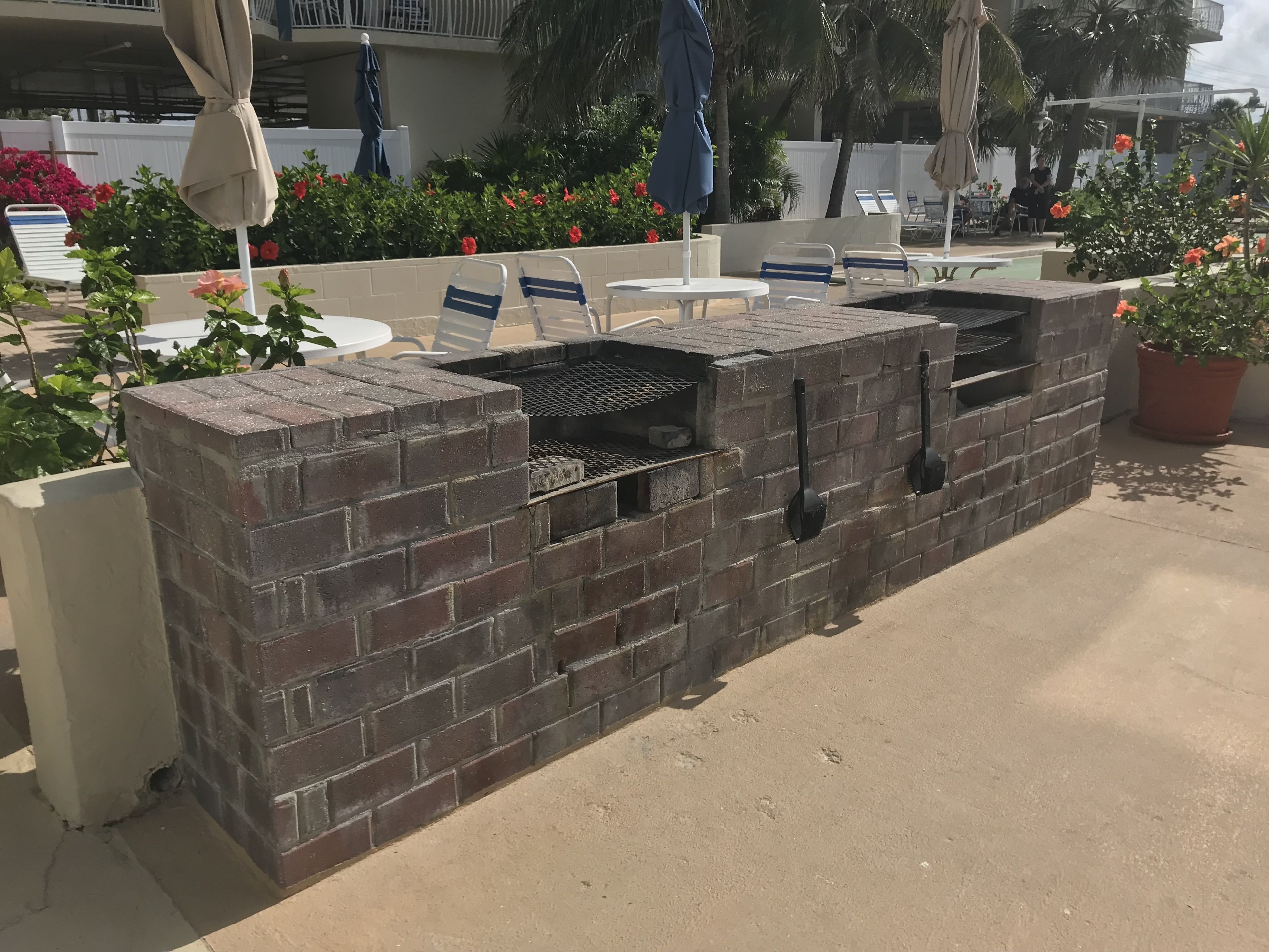 Eine Terrassengruppe mit gemauertem Grill, Liegestühlen und einem kleinen Tisch.