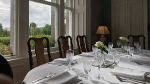 Comedor con mesa lista para una comida, ventanas amplias y vista a la vegetación.