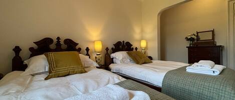 A hotel room with two beds, each with white linens and decorative pillows. There are bedside lamps and a dresser with a mirror.