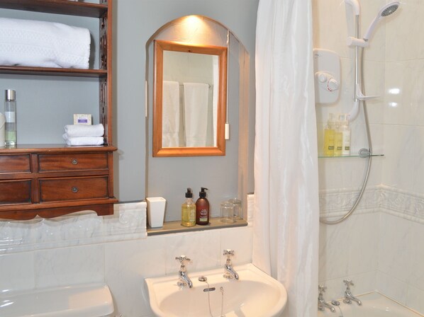 A bathroom with a wooden vanity, a large mirror, a shower, and a sink.