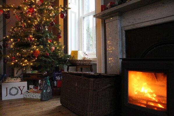 Una habitación acogedora con un árbol de Navidad decorado, una chimenea y un letrero que dice 'JOY'.