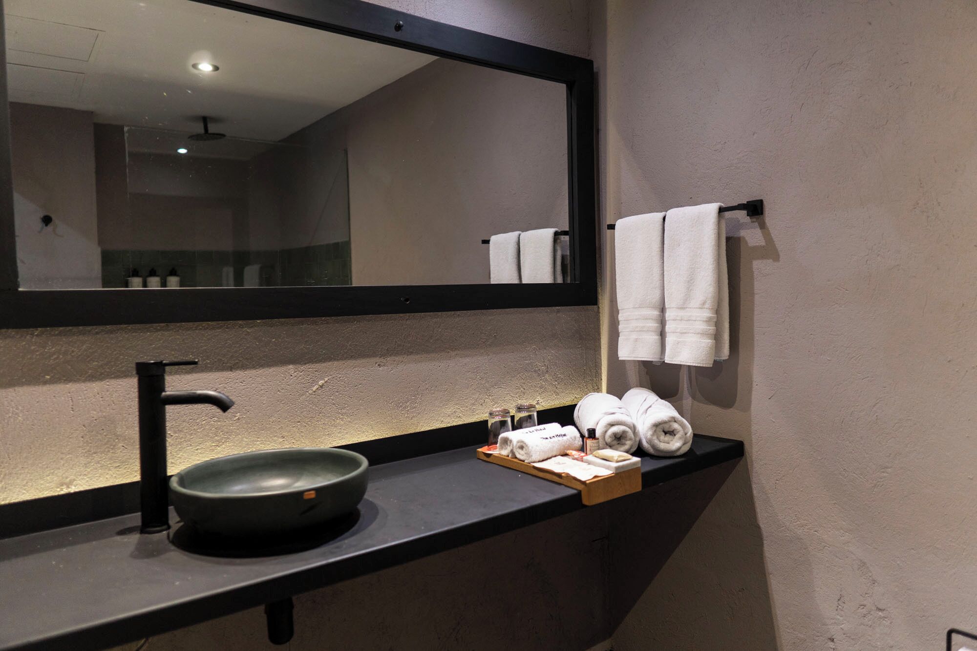 A bathroom with a black sink, a mirror, and towels.