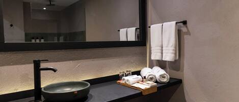 A bathroom with a black sink, a mirror, and towels.