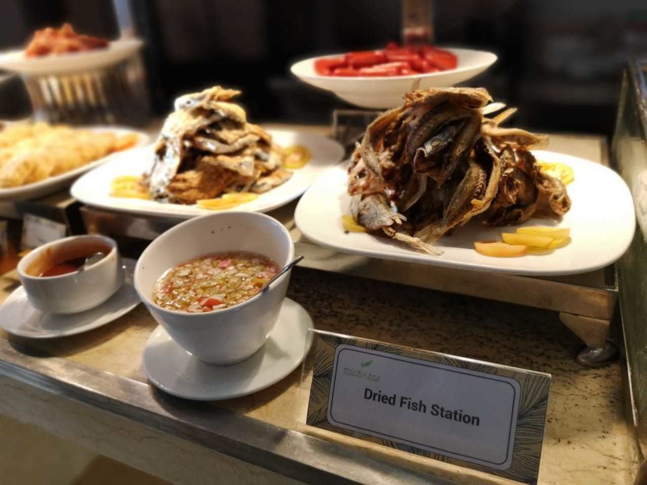 A food station with dried fish and a bowl of soup.
