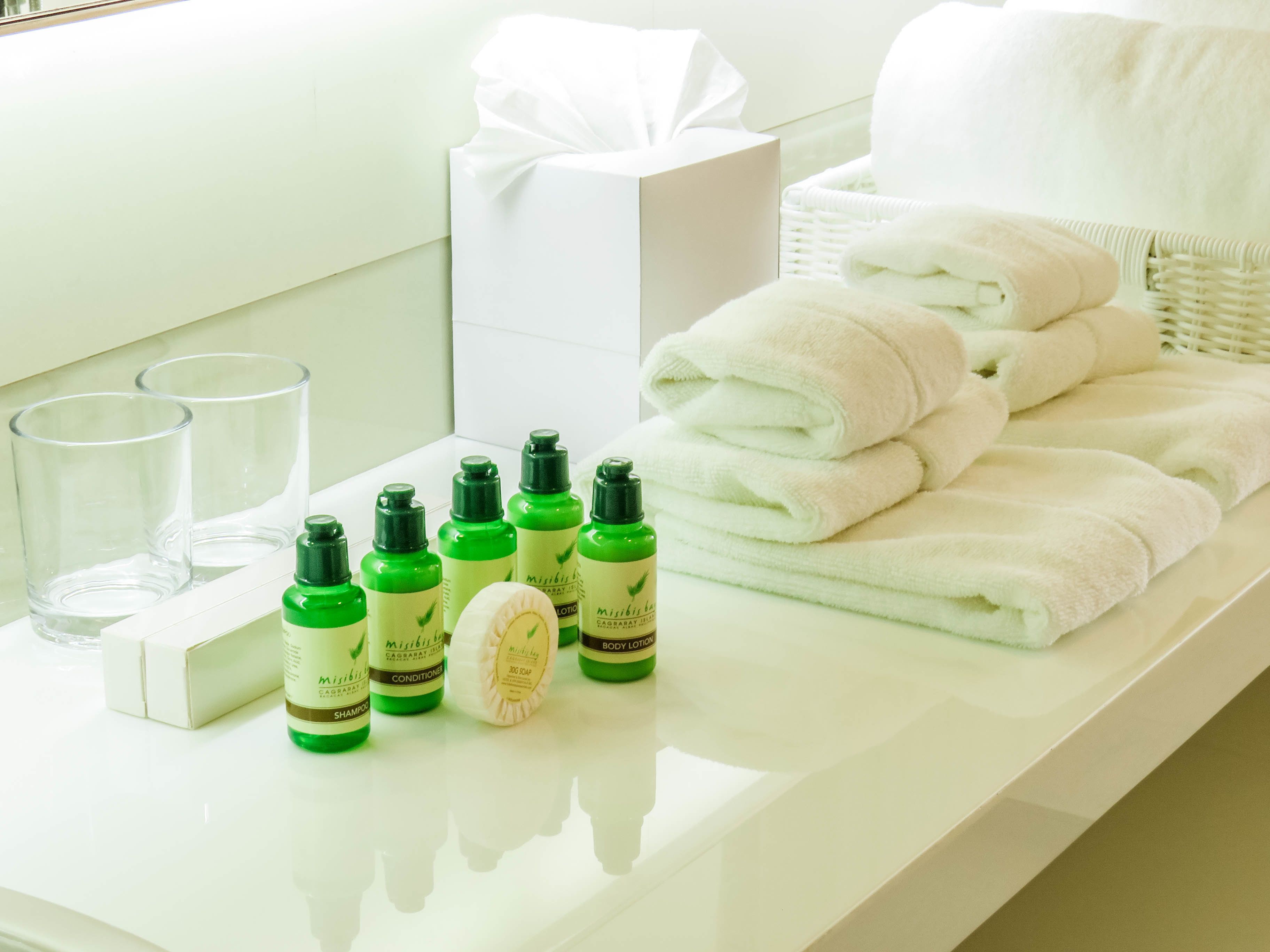 Una encimera de baño con artículos de aseo, toallas y una caja de regalo.