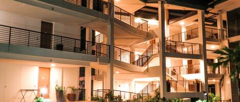 A multi-story hotel with a central atrium, balconies on each floor, and a landscaped courtyard.