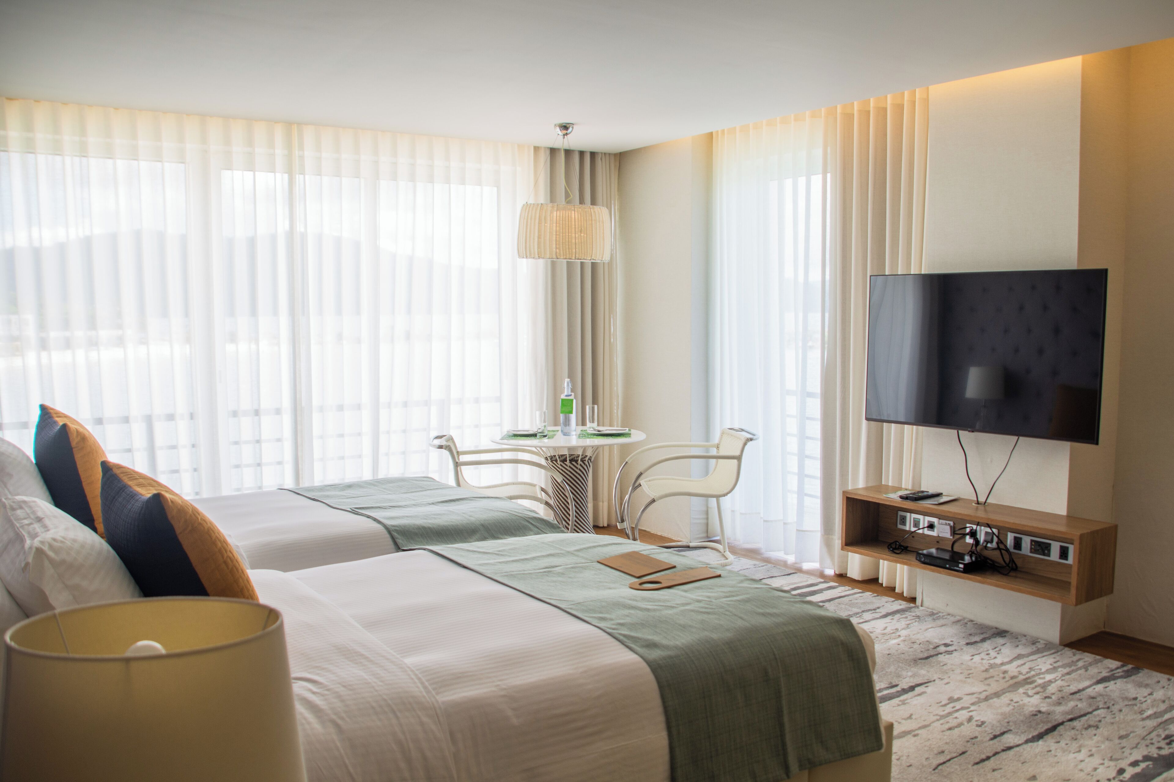 A hotel room with two beds, a TV, a desk, and a chair.