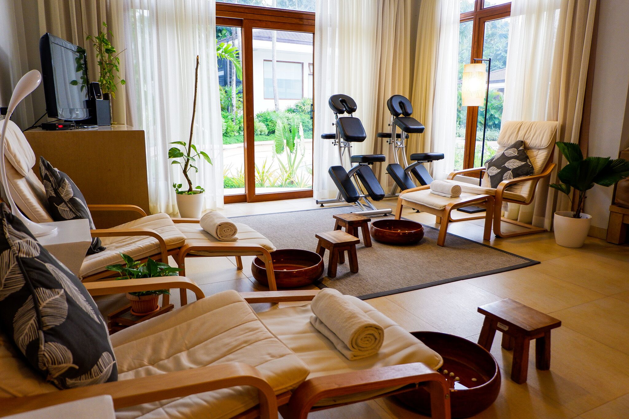A spa room with multiple massage chairs, a television, and a view of the garden.