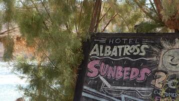 A sign for Hotel Albatross with 'Sunbeds' and 'Hot Shower' features.