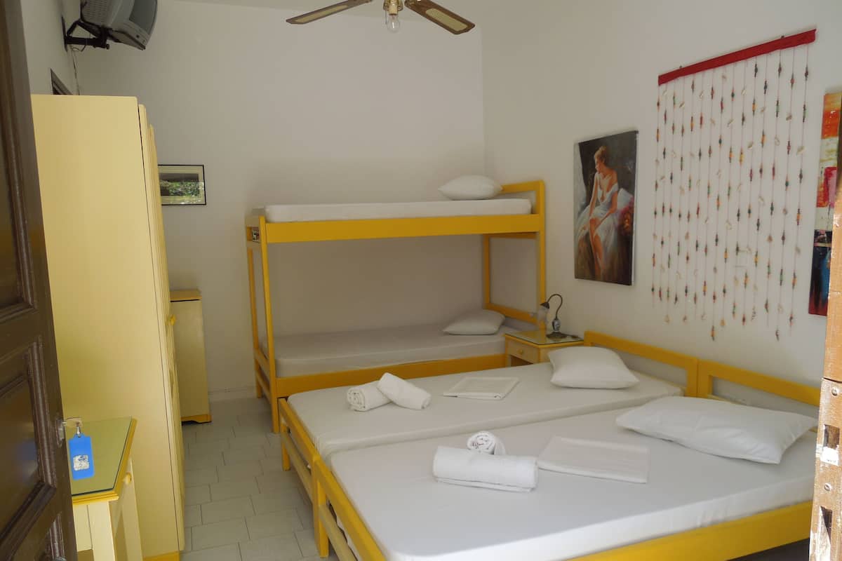 A bunk bed room with a desk, a ceiling fan, and a wall decoration.