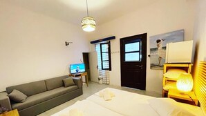 Habitación de hotel con cama, sofá, escritorio con computadora, puerta y ventana.