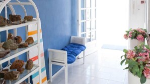 Una habitación con pared azul, un banco blanco, una araña y un cuadro de una escena costera.